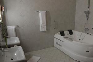 a white bathroom with a tub and a sink at Hotel Slavia in Salonta