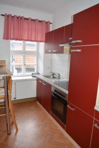 クヴェードリンブルクにあるTheophano´s Appartements im Kornmarktのキッチン(赤いキャビネット、シンク、窓付)