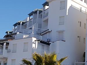 un edificio blanco con balcones y palmeras en Apartamento Santa Barbara, en Conil de la Frontera
