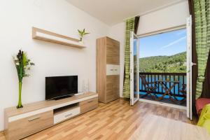 a living room with a television and a balcony at Apartments Matana Chano in Polače
