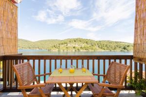a table and two chairs on a balcony with a view of a lake at Apartments Matana Chano in Polače