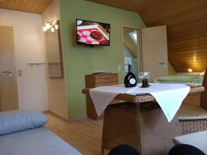 a room with a table and a tv on the wall at Pension "Der Sulzbachhof" in Lehrberg