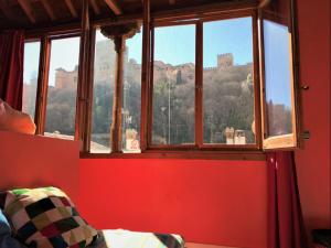 1 dormitorio con ventana y vistas a la montaña en White Nest Hostel, en Granada