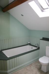 a bathroom with a bath tub and a toilet at The Byre in Keswick