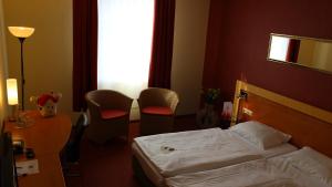 ACHAT Hotel Monschau في مونشاو: غرفة فندقية بسرير وطاولة وكراسي