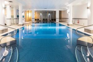 a large room with a pool, chairs, and a tub at Leonardo Royal Southampton Grand Harbour in Southampton