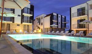 a swimming pool with chairs and umbrellas next to buildings at Seaside Apartment NLV in Sunny Beach