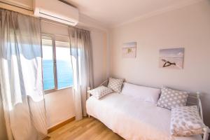 ein Schlafzimmer mit einem Bett und einem großen Fenster in der Unterkunft Piso primera línea de playa in Málaga