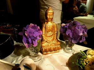 Spa e Hotel Fazenda Gaura Mandir في تيريسوبوليس: تمثال ذهب يجلس على طاولة مع الزهور الأرجوانية