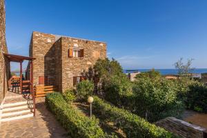 una casa in pietra con scala e l'oceano sullo sfondo di AffittaSardegna-Casa Lentischio a Stintino