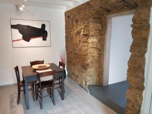 a dining room with a table and chairs and a stone wall at Ca' Irri Rent in Baveno