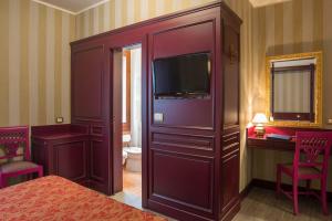 a bedroom with a large cabinet with a television in it at Hotel La Fenice et Des Artistes in Venice