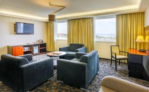 a hotel room with couches chairs and a television at Meresuu Spa & Hotel in Narva-Jõesuu