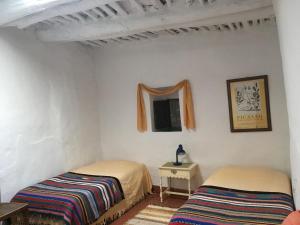 Habitación con 2 camas, mesa y espejo. en Casa Barbara, en Ferreirola