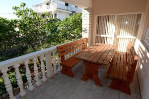 eine Holzbank auf dem Balkon in der Unterkunft Apartment Kod Stipe in Vrsi