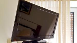 a flat screen tv sitting on a stand in front of a window at B&B Hotel Dolomiti in Bolzano