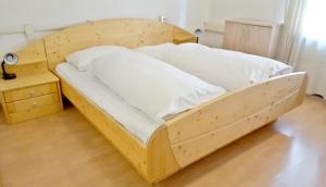 een houten bed met witte lakens en een nachtkastje bij B&B Hotel Dolomiti in Bolzano