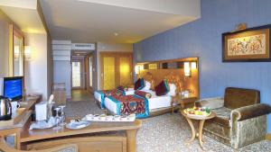 クンドゥにあるロイヤル ホリデイ パレスのベッドとリビングルームが備わるホテルルームです。