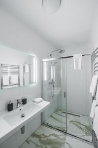 a white bathroom with a shower and a sink at Lazenska N4 Residence in Prague