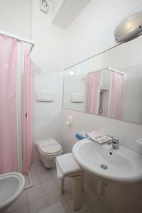 a white bathroom with a sink and a toilet at Hotel Hollywood in Senigallia