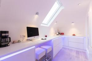 a white kitchen with a desk with a computer on it at ALTIDO Pleasant 2-bed flat near River Thames in London