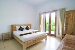 a bedroom with a bed and a large window at The Wina Guest House 2 in Canggu
