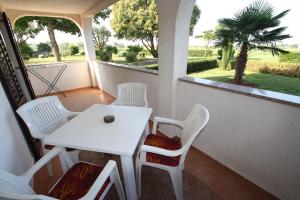 a white table and chairs on a balcony with a table and a window at Apartments Livio Stranici in Rošini +15 photos