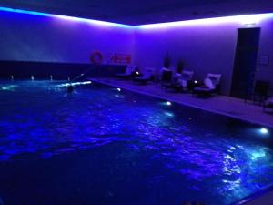 ein großes Schwimmbecken mit violetten Lichtern in einem Zimmer in der Unterkunft Patio Mare in Sopot