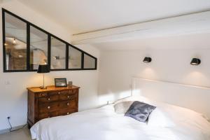 a bedroom with a white bed and a wooden dresser at le gîte de Montagnac in La Roque-sur-Cèze +49 photos