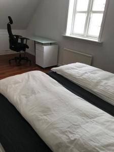 Duas camas num quarto com uma secretária e uma cadeira. em Hotel Nuuk - Apartment Nanoq em Nuuk