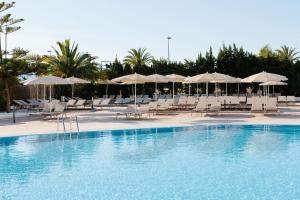 una piscina con sillas y sombrillas blancas en Bordoy Alcudia Bay - Adults Only en Port d'Alcudia