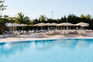 una piscina con sillas y sombrillas blancas en Bordoy Alcudia Bay - Adults Only, en Puerto de Alcudia