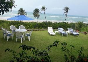 Casa de Praia em Mundaú في مونداو: مجموعة كراسي وطاولة مع مظلة