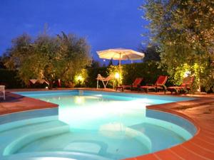 a swimming pool at night with an umbrella at Hotel Forum in Foiano della Chiana