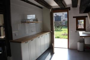 a kitchen with white cabinets and a door to a yard at Gîte Chevannes in Fours