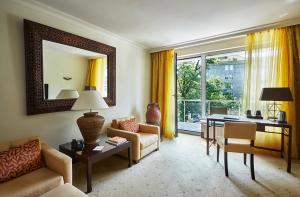 a living room with a couch and a desk and a mirror at Bernstein Hotel Villa Kastania in Berlin