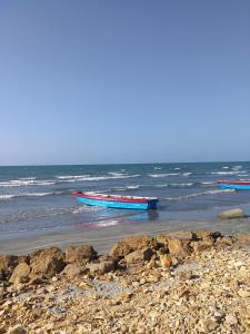 tres barcos sentados en el agua en una playa en Miraluna Hotel Boutique, en Coveñas