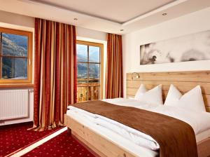 a hotel room with a large bed and a window at Naturresort Senningerhof in Bramberg am Wildkogel
