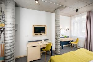 a room with two beds and a desk and a tv at Jam Hotel Hnatyuka in Lviv