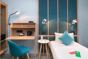 a room with a bed and a table and a chair at Hôtel Sanso by HappyCulture in Paris