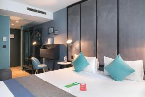 a hotel room with a bed with blue pillows at Hôtel Sanso by HappyCulture in Paris