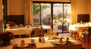 a restaurant with tables and chairs and a large window at De Vagebond Hotel-Pension in Windhoek