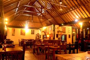 ein Restaurant mit Holztischen und Stühlen in einem Raum in der Unterkunft Sama Sama Amed in Amed