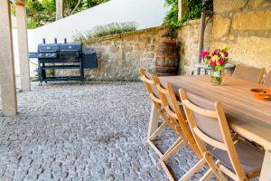 a table and chairs in a patio with a grill at Casa da Oliveira in Mondim de Basto