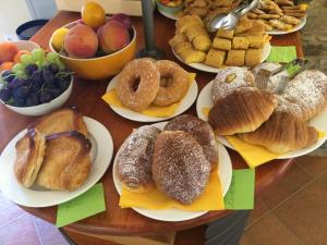 una tavola piena di diversi tipi di prodotti da forno su piatti di Locanda Il Monastero a Ortonovo