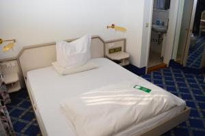 a bed with white sheets and pillows in a room at Boardinghaus zu Coburg Residenz in Coburg