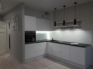 カトヴィツェにあるActivTower Apartamentのキッチン(白いキャビネット、黒いカウンタートップ付)