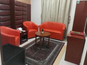 a living room with two orange chairs and a table at Al Aseel Ajyad in Mecca