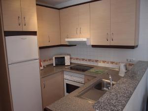 a kitchen with a white refrigerator and a sink at Tranquil apartment close to pool in Águilas