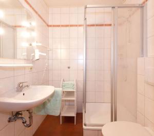 uma casa de banho branca com um lavatório e um chuveiro em Hofstub´n em Eschlkam